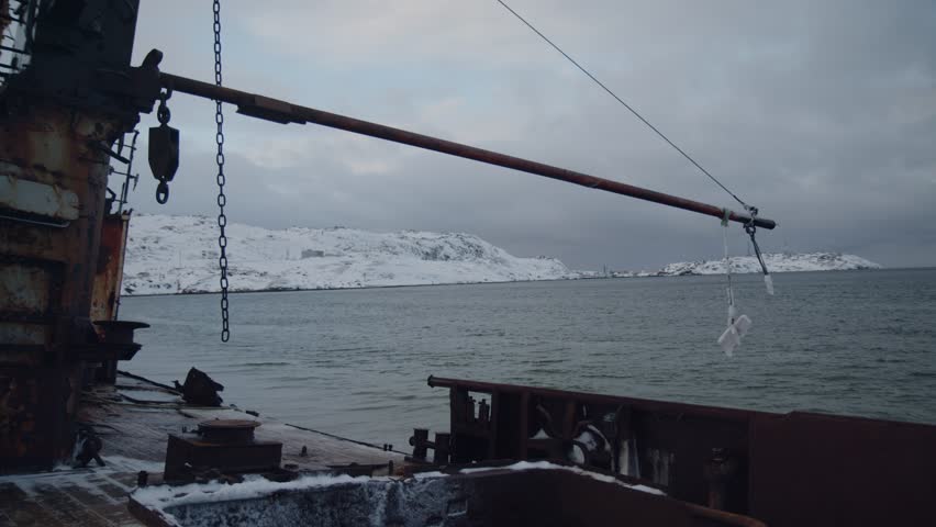 Waves of north sea bay beating old rusty deck fishing ship. Winter snow fjord