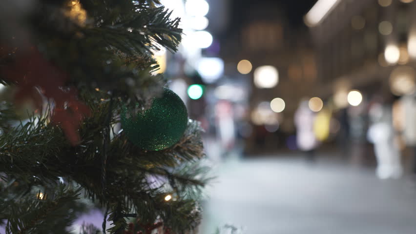 An ornament on a Christmas tree with a blurred night street background.