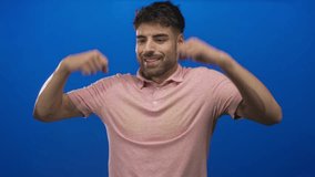 Young man with clenched fists and a broad smile in a bright blue studio; pride confidence ambition motivation. - Powered by Shutterstock - Get 15% off with code: PIKWIZARD15