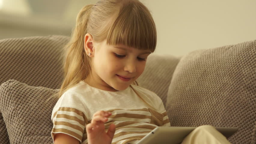 Cute girl playing on the tablet and smiling
