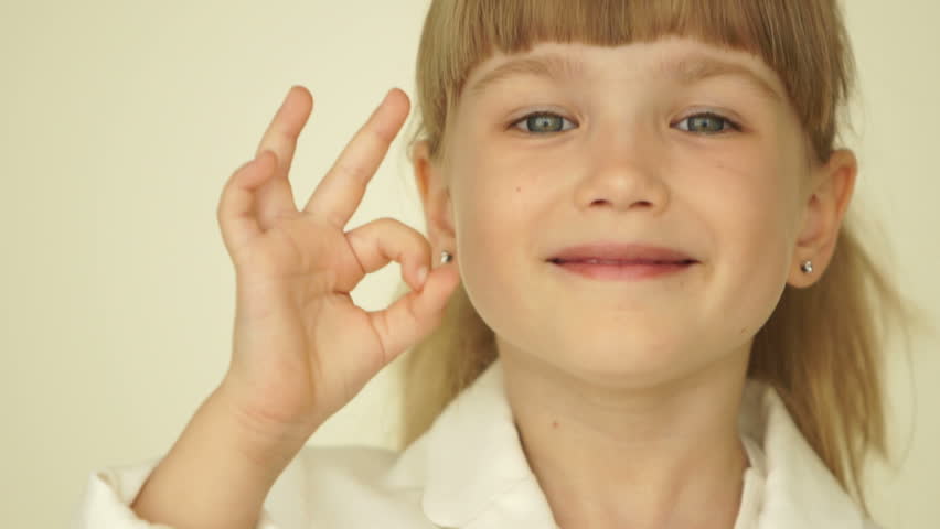 Little girl with ok hands sign nods her head
