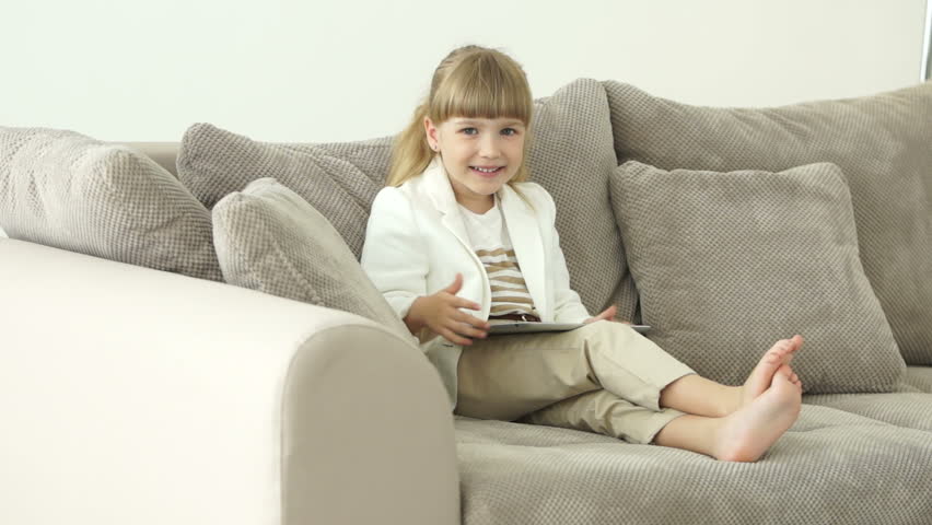 Girl on the couch with tablet rejoices
