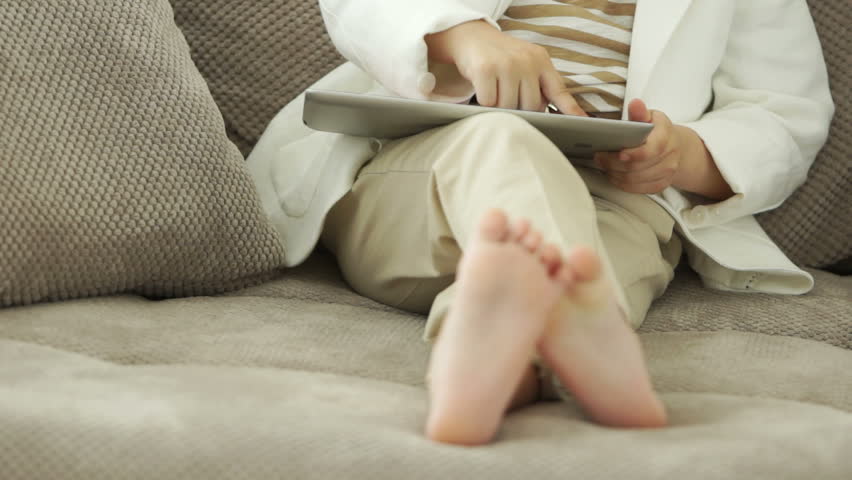 Girl sitting with tablet and wagging her feet

