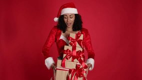 Beautiful woman in Mrs Claus costume with Christmas gifts on red background - Powered by Shutterstock - Get 15% off with code: PIKWIZARD15