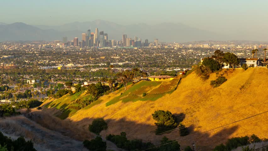 Los Angeles. Aerial view of a cityscape with a mountain range in the background. The city appears to be Los Angeles, as indicated by the buildings and hills.