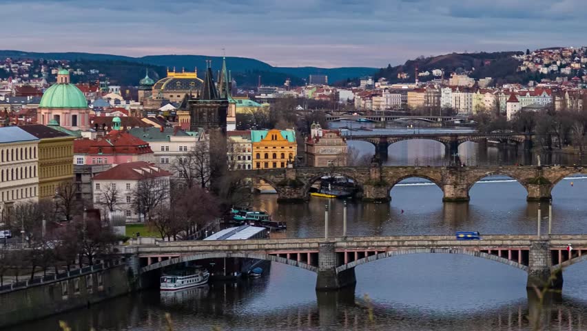Prague. Aerial view of historic cityscape during sunset with river and bridge in foreground.