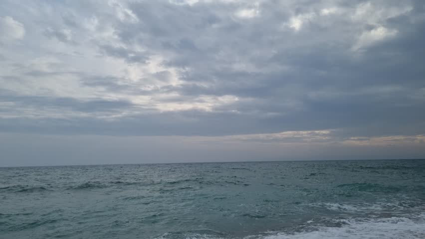 Dynamic seaside waves rolling under dramatic cloudy sky, capturing the energy of the stormy shoreline and the constant movement of the restless sea water today