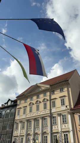 The Slovenian flag, the EU flag, and the Ljubljana flag on a building, vertical video.