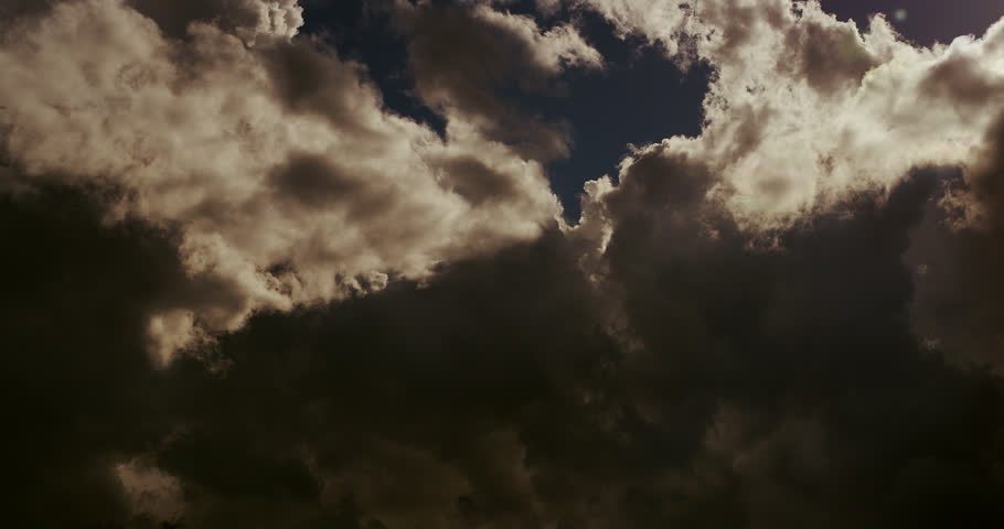 Towering storm clouds cloak the storm’s base in dark shadow, sharply contrasting the interplays of shadow and light in nature.