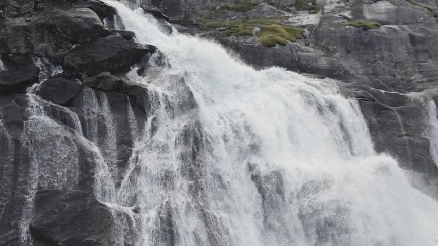 Aerial footage of a powerful waterfall in Rago National Park, Norway. Clear mountain water cascades down dramatic cliffs surrounded by rugged wilderness and pristine Nordic nature.