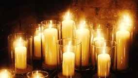 A group of lit ivory pillar candles in clear glass holders arranged closely together, casting a golden glow against a rustic brick wall background. - Powered by Shutterstock - Get 15% off with code: PIKWIZARD15