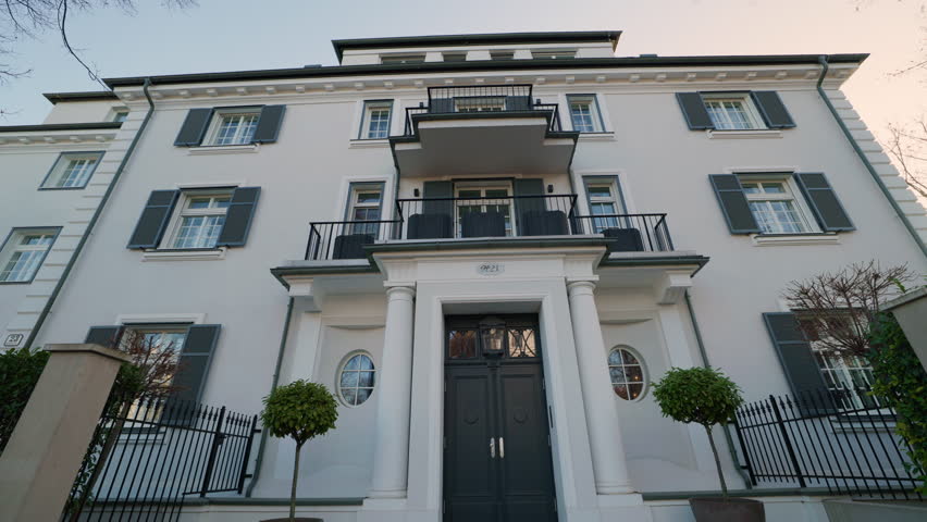 Entrance of vintage building with classic columns and shutters on windows low angle shot. Apartment house combines modern and traditional luxury styles