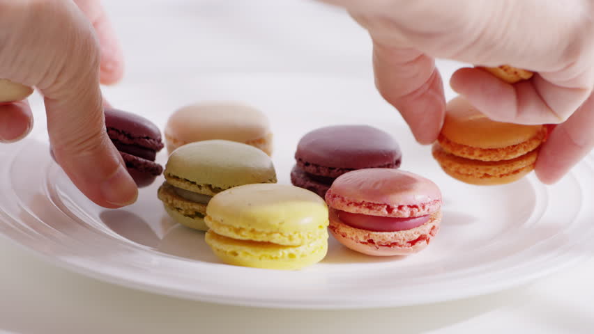 Collection of colorful macarons in various shades sits casually arranged on a plate. 