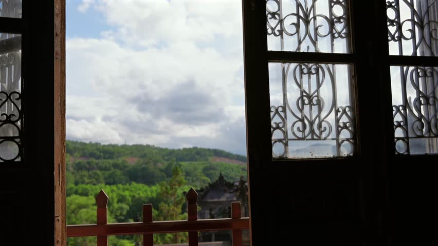 Framed view of a stone pillar and lush green mountains under a dramatic cloudy sky at Khai Dinh Mausoleum.
