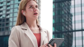 Professional young caucasian businesswoman talking using wireless earbud while holding digital tablet outdoors in city, business woman using technology for communication and success in urban. - Powered by Shutterstock - Get 15% off with code: PIKWIZARD15