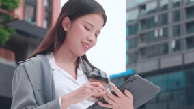 Happy young asian businesswoman standing holding coffee while using tablet outdoors city, digital nomad, business woman or manager touching tablet for working, modern technology, digital device. - Powered by Shutterstock - Get 15% off with code: PIKWIZARD15