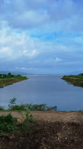 Cyclist Riding Bike near Lake Under Cloudy Sky. Cyclists Cycling Near Limboto Lake Under Cloudy Skies on a cloudy morning