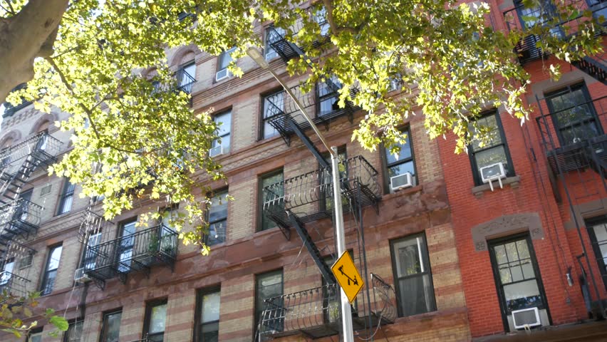 New York City urban residential buildings architecture, Manhattan classic street, United States of America. Typical red brick house in NYC, real estate property in USA. Fire escape metallic ladder.