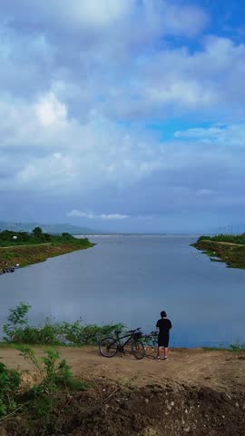 Cyclist Overlooking Lake Limboto in Gorontalo, Indonesia. Cyclists Cycling Near Limboto Lake Under Cloudy Skies on a cloudy morning