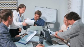 A diverse group of professionals engaged in a project discussion in a modern office setting. Men and women reviewing charts, working on laptops, analyzing documents together during a business meeting. - Powered by Shutterstock - Get 15% off with code: PIKWIZARD15
