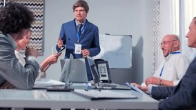 Confident male employee in formal blue suit presenting a business strategy on a whiteboard during a team meeting. Office setting with colleagues listening attentively. Planning process, and teamwork. - Powered by Shutterstock - Get 15% off with code: PIKWIZARD15