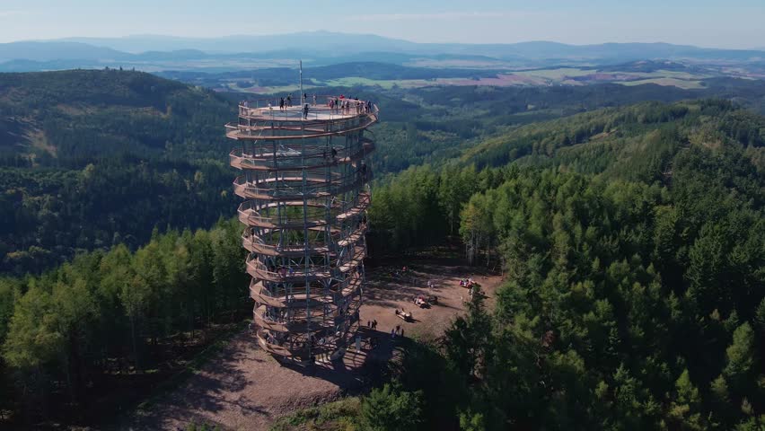 Aerial panoramic view of observation tower on forested mountain hill. Natural vast landscape with forest and distant ridges