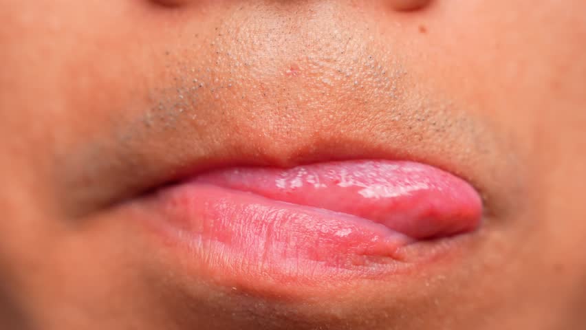 A person purses their lips and circles their tongue around, an action commonly linked to nervousness, internal conflict, or a need for comfort, revealing hidden feelings or suppressed emotions.
