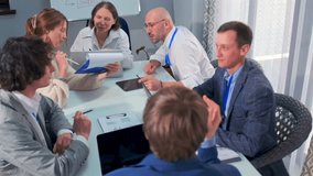 Diverse group of colleagues having a strategic discussion in modern office. They are reviewing documents, pointing at graphs, and exchanging ideas with laptops on the table. Concept of teamwork. - Powered by Shutterstock - Get 15% off with code: PIKWIZARD15