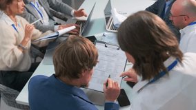 Female assistant interrupts a tense office meeting to get a document signed by the team leader. Group of professionals working under deadline pressure. Business stress and multitasking. - Powered by Shutterstock - Get 15% off with code: PIKWIZARD15