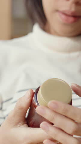 Vertical Screen : Sick young Asia woman holding pill take a look medicine sit on couch at home. Girl taking medicine after doctor order, quarantine at house, Coronavirus social distancing concept.