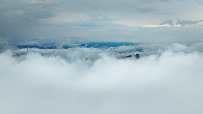 Aerial shot of majestic mountain peaks rising above thick white sea of clouds nature landscape