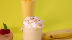 Hand places striped straw into creamy banana milkshake topped with whipped cream and sprinkles - Powered by Shutterstock - Get 15% off with code: PIKWIZARD15