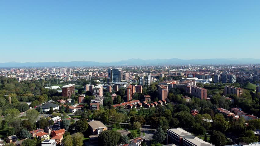 Aerial view of Milan’s skyline, showcasing a mix of modern skyscrapers and historic architecture with mountains italian alps in background
