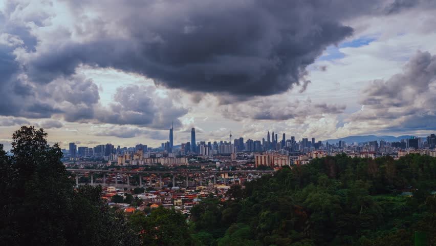 Panoramic view of the city skyline, including the TRX Exchange 106 and Petronas Towers, under heavy, dark storm clouds from a high vantage point.