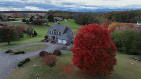 Aerial revealing shot of red colored tree in front of rural single family house with Pond in America. Autumn season in Virginia, USA. Patriotic and proud family with waving American flag. - Powered by Shutterstock - Get 15% off with code: PIKWIZARD15