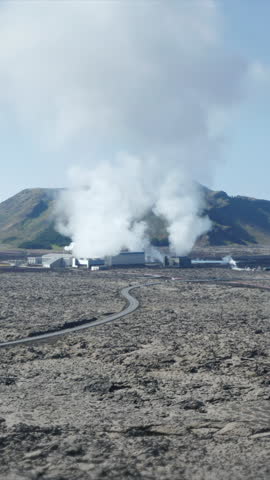 Aerial ascending footage of factory or power plant emitting smoke. Scene overlayed by rising chart. Iceland