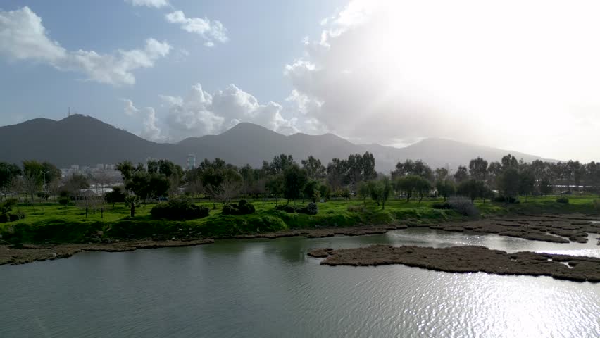 Aerial View of River and Park with Mountains in Dramatic Sunlight