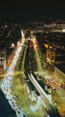 Forwards fly above busy multilane thoroughfare with elevated ubahn tracks. Aerial view of evening city. Vienna, Austria. Added augmented reality visual effects