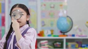Young girl inspects through magnifying glass in colorful classroom, bright lighting, static camera - Powered by Shutterstock - Get 15% off with code: PIKWIZARD15