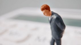 A Miniature Businessman Figurine Bowing Its Head On A Blurred Calculator, Reflecting Financial Stress Or Contemplation. - Powered by Shutterstock - Get 15% off with code: PIKWIZARD15