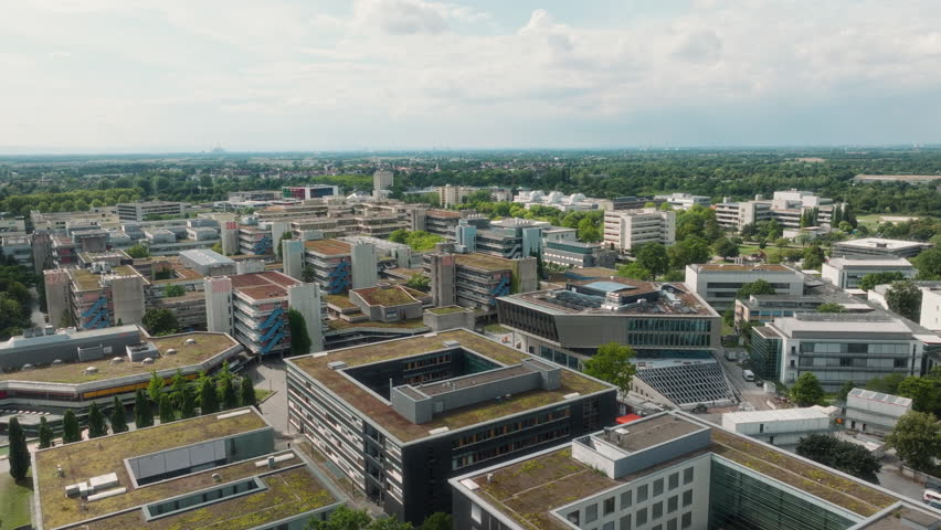 Drone pulling back diagonally with tilt-down revealing Bahnstadt’s inner courtyards and green roofs.