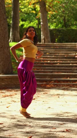 Smiling woman performing a traditional indian dance in a public park. Graceful movements and cultural expression during an outdoor performance