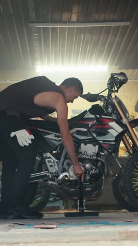 A dedicated rider fine-tunes a sleek motorbike in a dimly lit workshop, surrounded by tools and the promise of speed. The atmosphere buzzes with enthusiasm