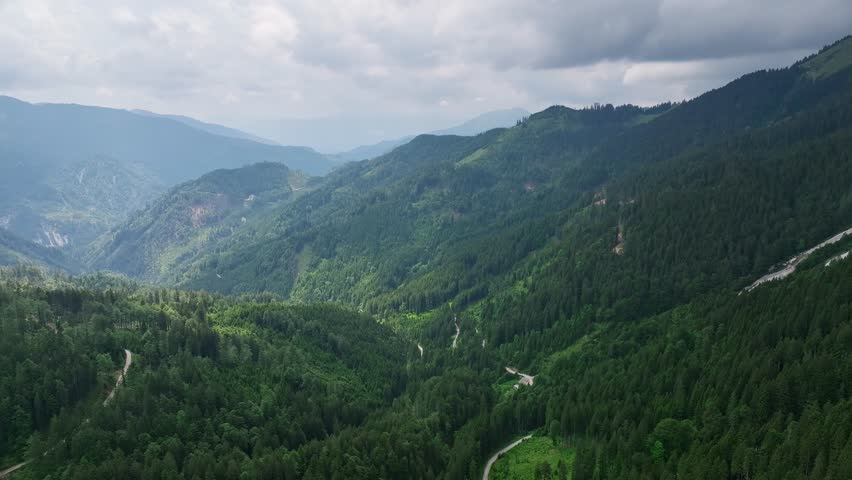 Cinematic aerial drone footage of Slovenia Alps. forest on cloudy summer day showing green mountain trees, peaceful atmosphere, natural landscape and calm outdoor alpine scenery