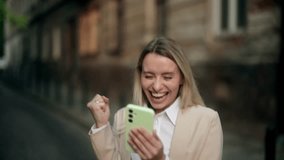Excited woman reading good news on smartphone outdoors, surprised and happy reaction. Emotional moment of joy and amazement on city street - Powered by Shutterstock - Get 15% off with code: PIKWIZARD15