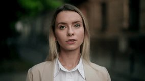 Serious woman looking straight at camera outdoors, confident and calm expression. Portrait of thoughtful professional on city street - Powered by Shutterstock - Get 15% off with code: PIKWIZARD15