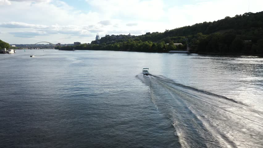 Aerial view of boats sailing on the Ohio River, with the Cincinnati skyline and lush green hills in the distance, Cincinnati, Ohio, United States.