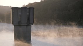 High quality video showing a concrete tower rising from the calm misty lake of the Wehebachtalsperre at sunrise with soft light, drifting fog and a quiet forest backdrop. - Powered by Shutterstock - Get 15% off with code: PIKWIZARD15