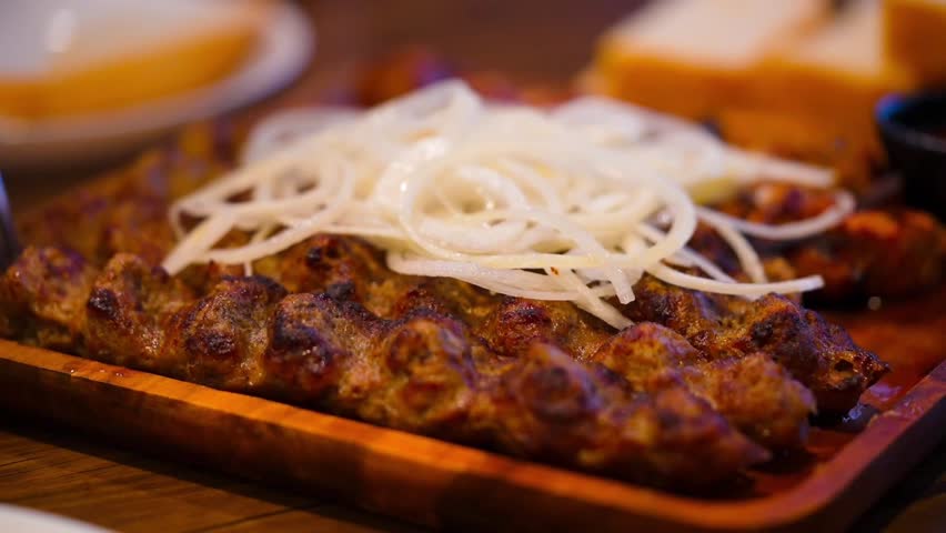 Tasty dish barbecue of meat with onion and sauce on plate, tasted with a fork