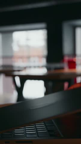 Vertical close-up showing a laptop lid being lifted from the left side. The blurred background and natural light highlight the clean workspace and the start of a work session. High quality 4k footage
